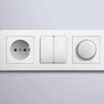Realistic white plastic panel with socket and single round and double rectangular switches on grey wall vector illustration